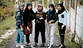 five young women wearing hijabs and dressed in very modern clothing such as jeans